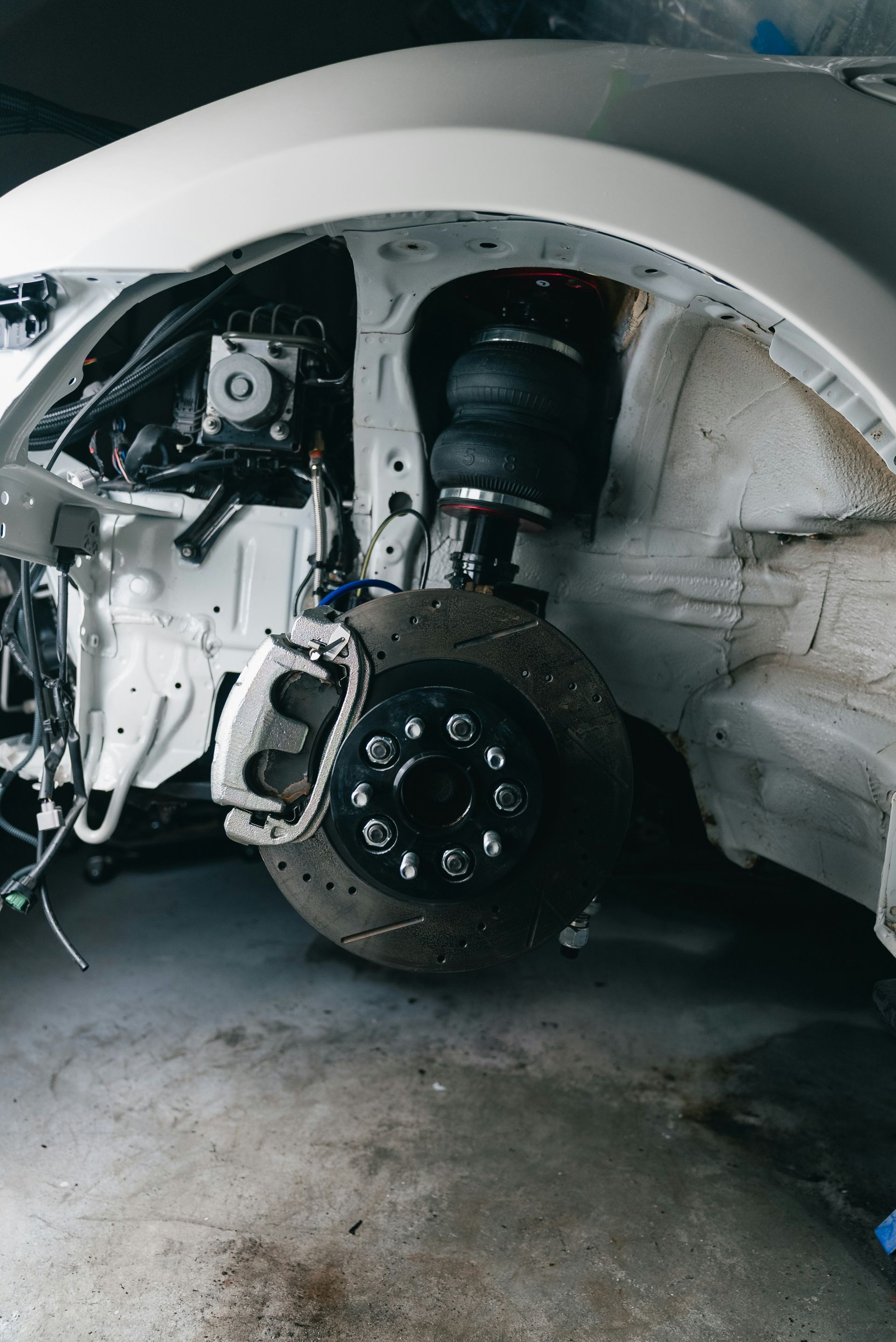 White car's disassembled front suspension and wheel assembly